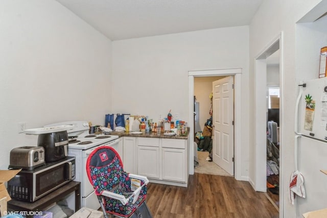 kitchen with dark wood-type flooring, white cabinets, and white appliances