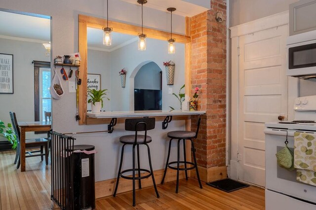 kitchen with pendant lighting, a breakfast bar area, white range with electric cooktop, crown molding, and light hardwood / wood-style flooring