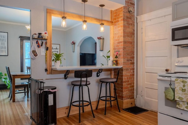 kitchen with pendant lighting, ornamental molding, a kitchen breakfast bar, white range with electric stovetop, and light wood-style floors