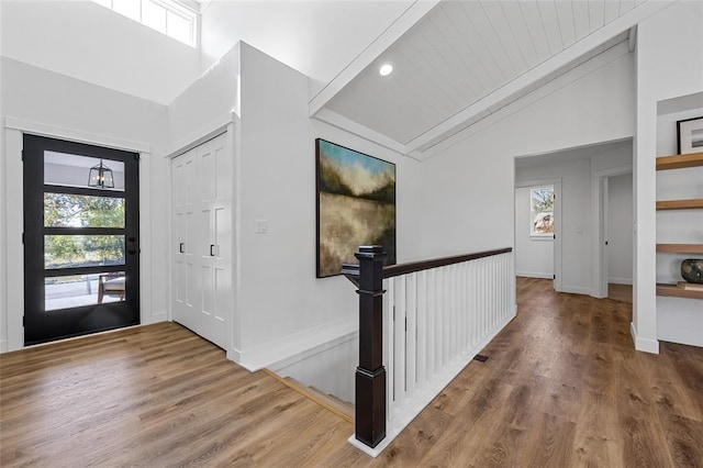 foyer with wood-type flooring and vaulted ceiling