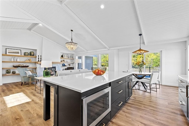 kitchen with built in microwave, a center island, pendant lighting, and vaulted ceiling with beams