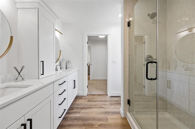 bathroom with wood-type flooring, a shower with door, and vanity