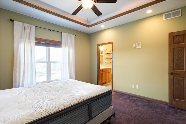 carpeted bedroom featuring ornamental molding, connected bathroom, ceiling fan, and a tray ceiling