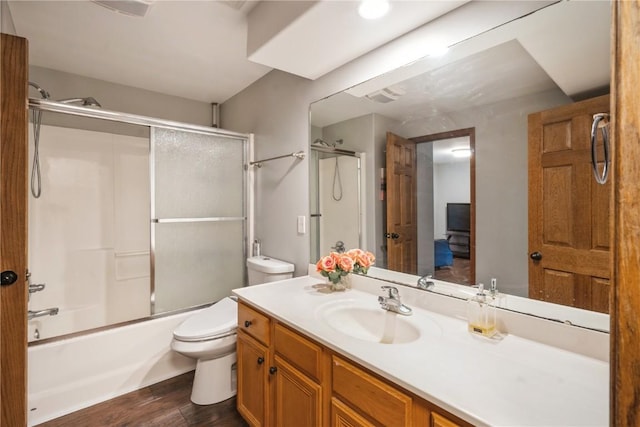 full bathroom featuring hardwood / wood-style flooring, enclosed tub / shower combo, vanity, and toilet