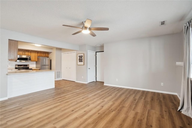 unfurnished living room with ceiling fan, a textured ceiling, and light wood-type flooring