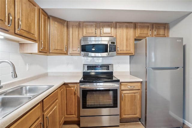 kitchen with appliances with stainless steel finishes, sink, and decorative backsplash