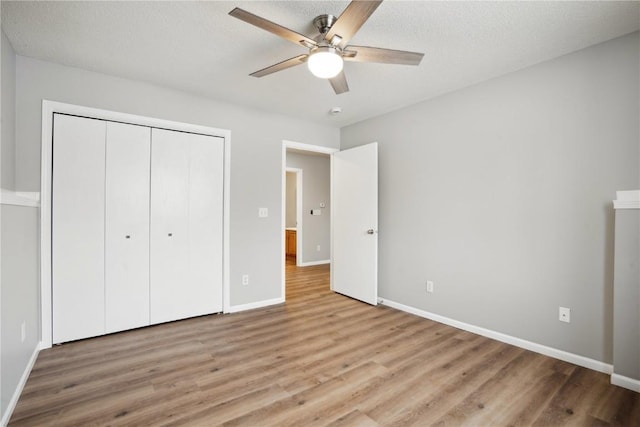 unfurnished bedroom featuring ceiling fan, a textured ceiling, a closet, and light wood-type flooring