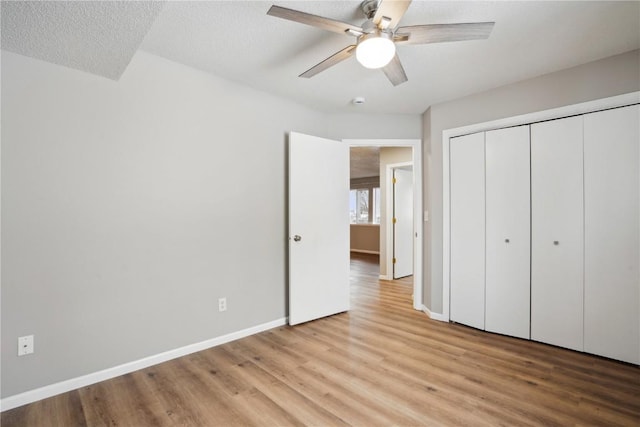 unfurnished bedroom with light hardwood / wood-style flooring, a textured ceiling, ceiling fan, and a closet