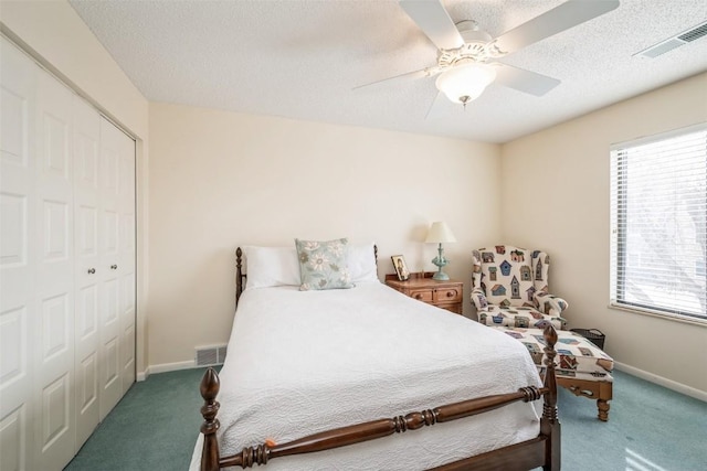 bedroom featuring ceiling fan, dark carpet, a closet, and a textured ceiling