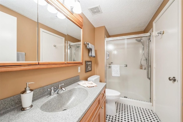 bathroom with a shower with door, vanity, a textured ceiling, and toilet