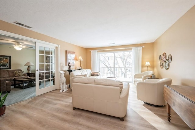 living room with french doors and light wood-type flooring