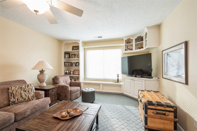 living room featuring ceiling fan, carpet floors, and a textured ceiling