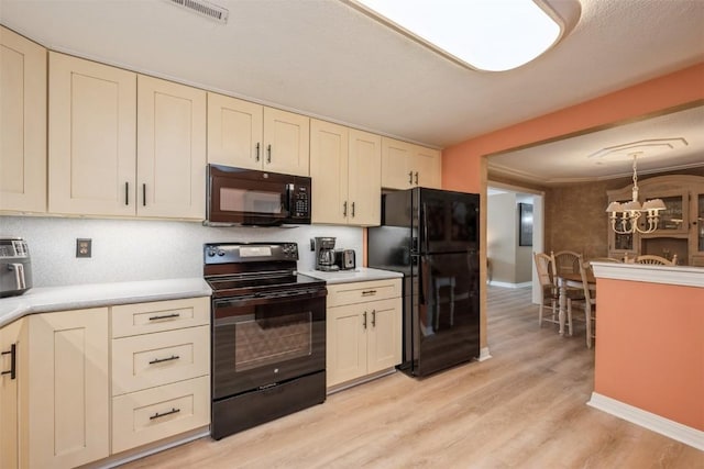 kitchen featuring cream cabinets, black appliances, and a chandelier