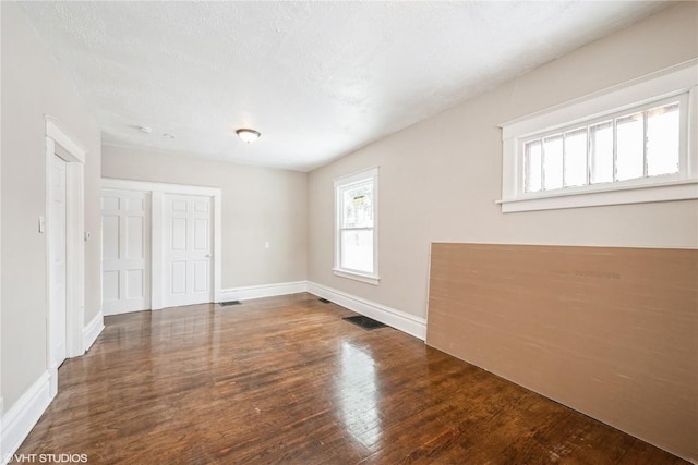 spare room featuring dark hardwood / wood-style flooring and a textured ceiling