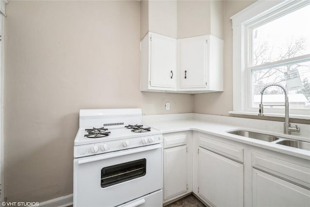 kitchen with sink, gas range gas stove, and white cabinets