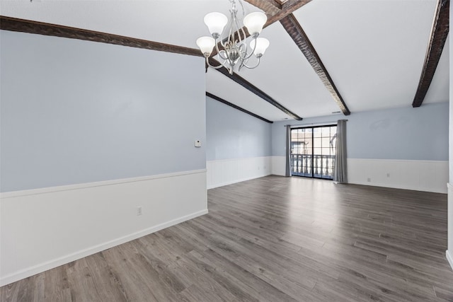 empty room featuring lofted ceiling with beams, dark wood-type flooring, and a chandelier