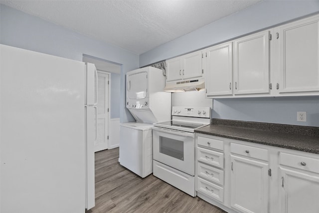 kitchen featuring white appliances, stacked washer / dryer, a textured ceiling, white cabinets, and light wood-type flooring