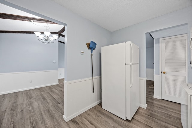 kitchen with a chandelier, hardwood / wood-style floors, white fridge, and a textured ceiling