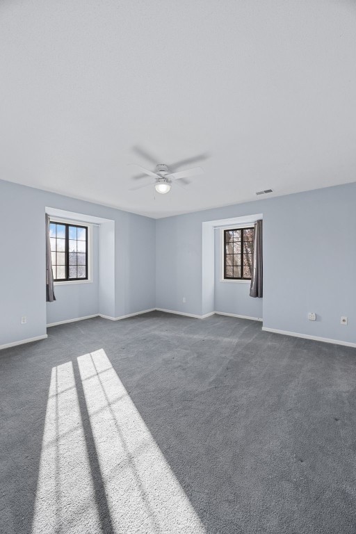 spare room featuring dark carpet and ceiling fan