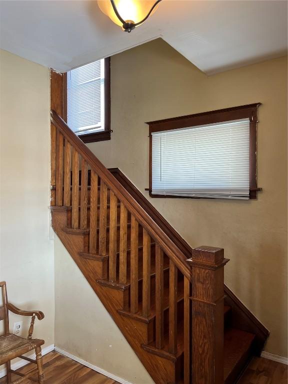 stairs with baseboards, vaulted ceiling, and wood finished floors