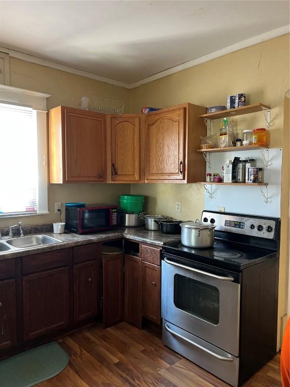 kitchen featuring dark wood-type flooring, a sink, stainless steel electric range, open shelves, and crown molding