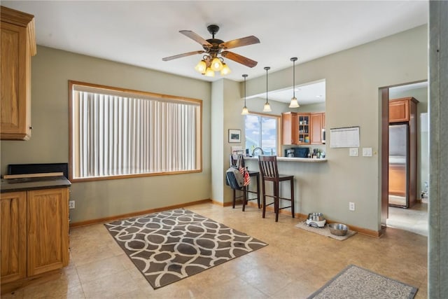 kitchen featuring decorative light fixtures, stainless steel refrigerator, a kitchen breakfast bar, kitchen peninsula, and ceiling fan