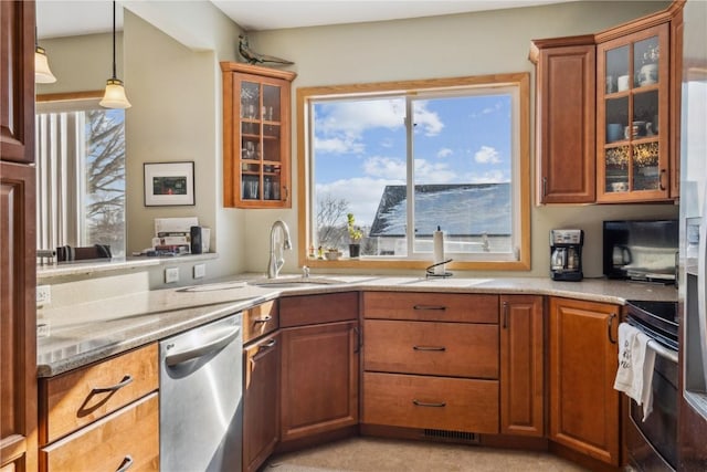 kitchen featuring light stone counters, sink, stainless steel appliances, and hanging light fixtures