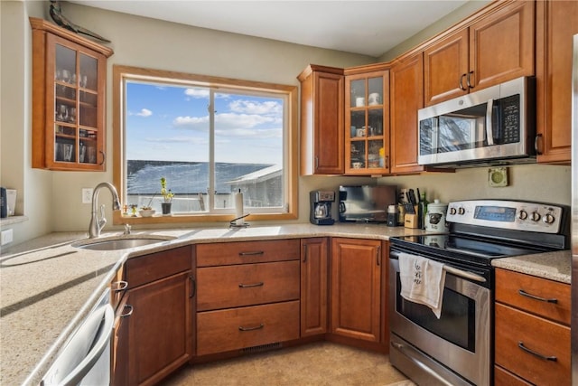 kitchen with light stone counters, stainless steel appliances, and sink