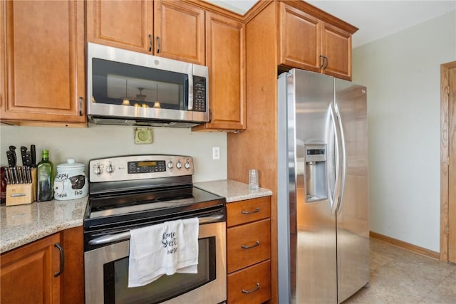 kitchen with light stone countertops and appliances with stainless steel finishes