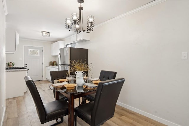 dining room featuring ornamental molding, a chandelier, and light hardwood / wood-style flooring