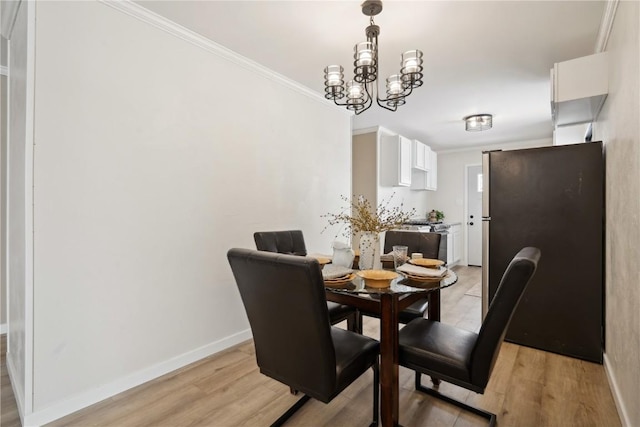 dining room with crown molding, an inviting chandelier, and light hardwood / wood-style floors