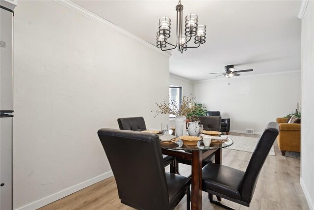 dining area with ceiling fan with notable chandelier, ornamental molding, and light wood-type flooring