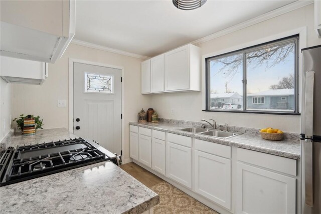 kitchen featuring white cabinetry, stainless steel fridge, gas range, and sink