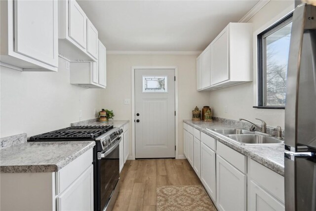 kitchen featuring sink, gas range, white cabinets, and light wood-type flooring