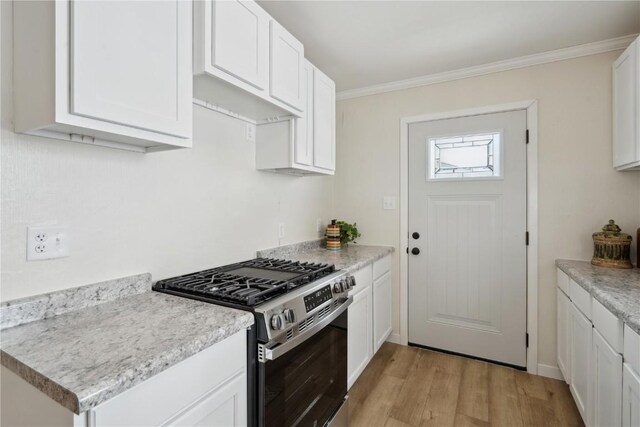 kitchen featuring white cabinetry, crown molding, light hardwood / wood-style flooring, and stainless steel gas range oven