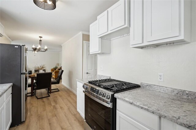 kitchen featuring white cabinetry, hanging light fixtures, ornamental molding, light hardwood / wood-style floors, and stainless steel appliances