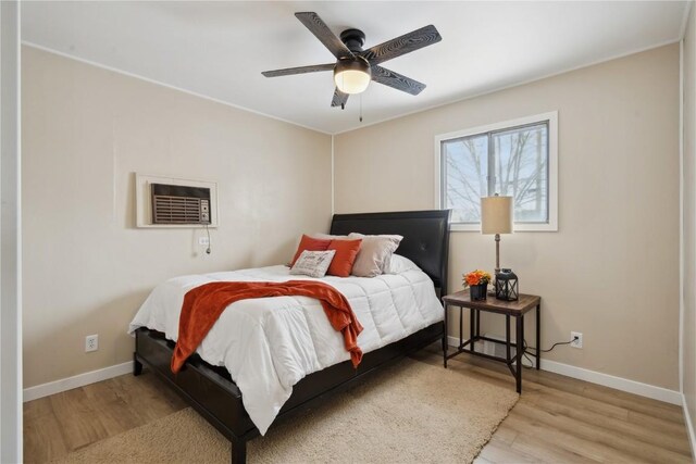 bedroom with a wall mounted air conditioner, ceiling fan, and light wood-type flooring