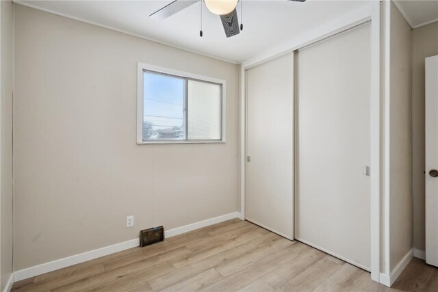 unfurnished bedroom with light wood-type flooring, ceiling fan, and a closet