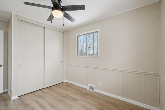 unfurnished bedroom with ceiling fan, a closet, and light wood-type flooring