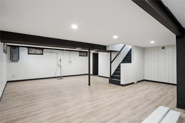 basement featuring electric panel and light hardwood / wood-style floors