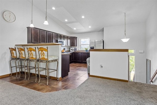 kitchen featuring appliances with stainless steel finishes, pendant lighting, dark tile patterned flooring, and dark brown cabinetry