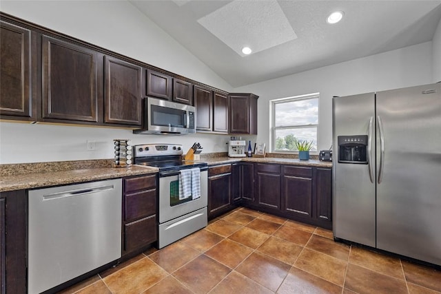 kitchen featuring dark brown cabinetry, stone counters, appliances with stainless steel finishes, dark tile patterned floors, and vaulted ceiling with skylight