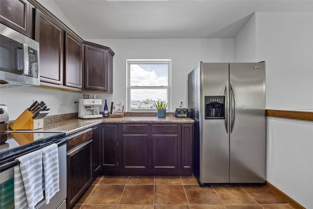 kitchen with appliances with stainless steel finishes, dark tile patterned flooring, and dark brown cabinetry