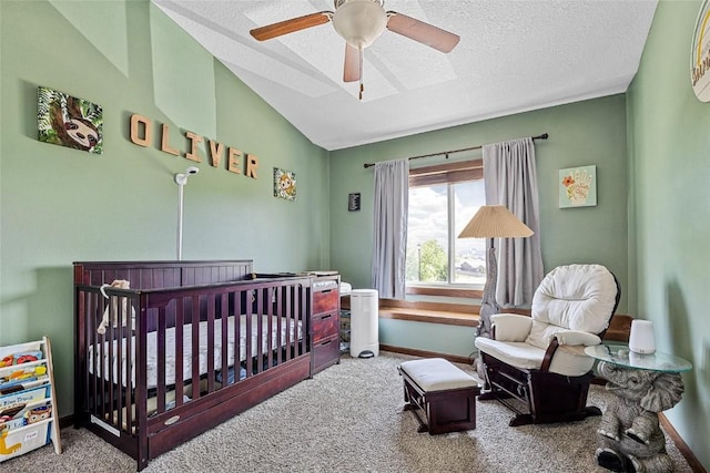 bedroom featuring lofted ceiling, ceiling fan, a nursery area, carpet flooring, and a textured ceiling