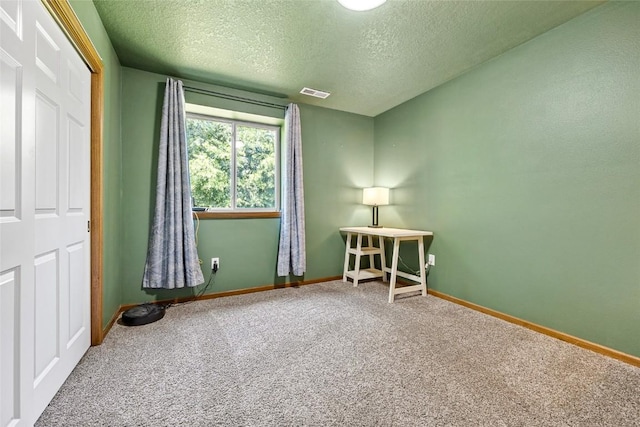 unfurnished room with carpet flooring and a textured ceiling