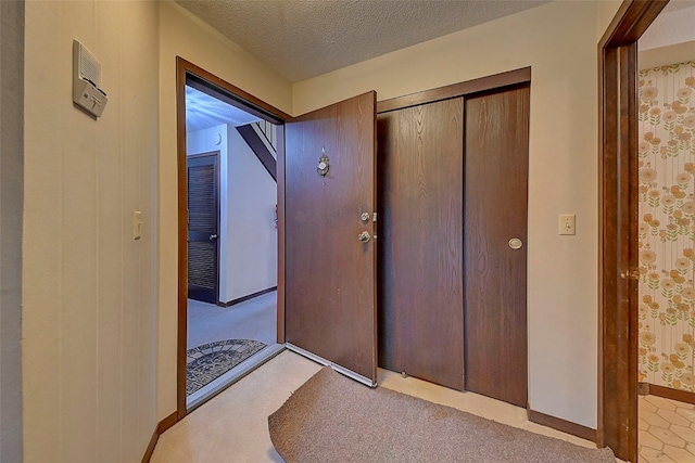 hall featuring light carpet and a textured ceiling