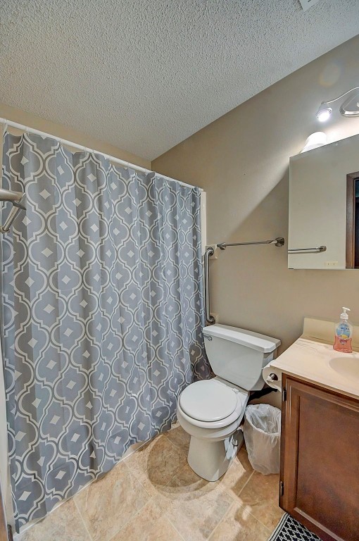 bathroom featuring vanity, a textured ceiling, and toilet