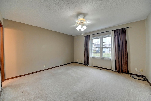 empty room with light colored carpet and a textured ceiling