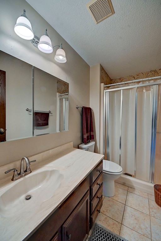 bathroom with walk in shower, tile patterned floors, vanity, and a textured ceiling