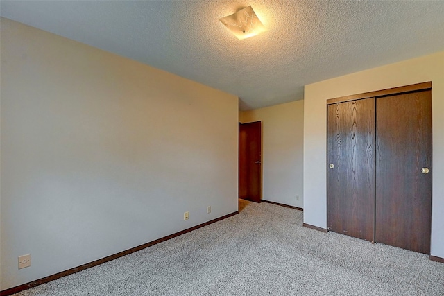 unfurnished bedroom with light carpet, a textured ceiling, and a closet